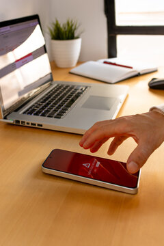 Hand reaching for smartphone with security alert on screen