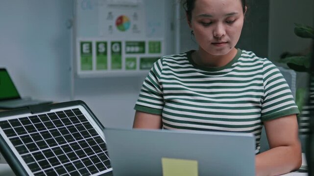 Businesswoman reviewing ESG reports and green business financial charts with a laptop and documents. ESG concept Environmental, Social, and Governance, eco-friendly green building, sustainable