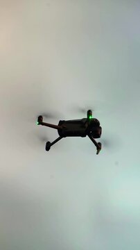 Black quadcopter drone hovering in mid air against bright sky