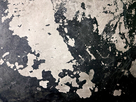 Peeling paint texture on dark concrete surface showing abstract organic shapes.