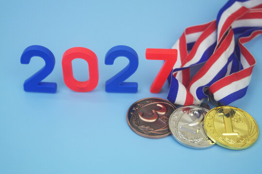 Gold, silver and bronze medal with numbers 2027 on blue background. Sport competitions in year 2027 concept.	