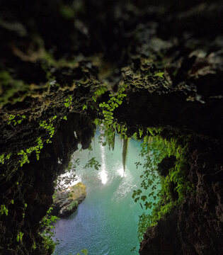 Waterfall flowing in front of a moss-covered cave