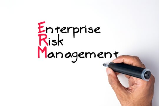 Hand holding a black marker writing the acronym ERM or Enterprise Risk Management on a white background. Corporate governance, audit compliance, business strategy concept.