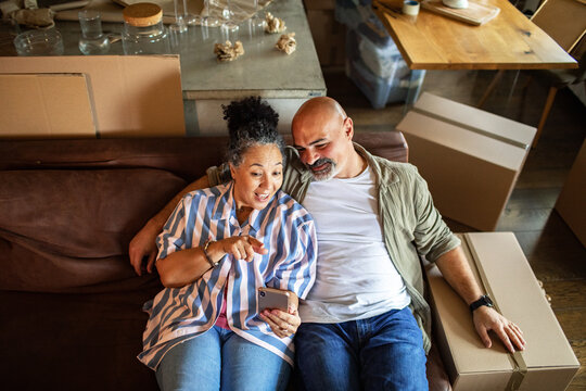 Happy couple looking at smartphone on couch while moving