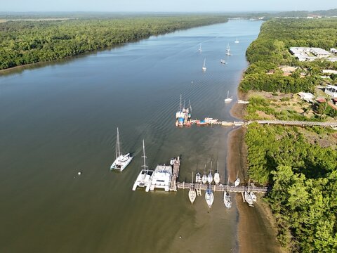 Aerial view of the Kourou River with a catamaran dock, boats, tropical vegetation and waterfront homes in Kourou, French Guiana.