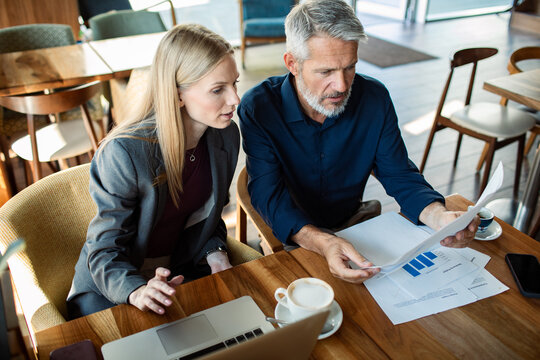 Coworkers reviewing financial report at cafe table