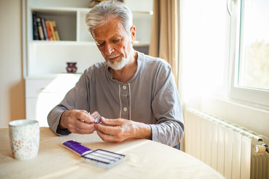 Senior man sorting pills into a pill organizer at home