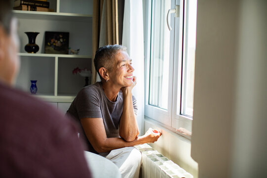 Smiling adult looking out the window at home