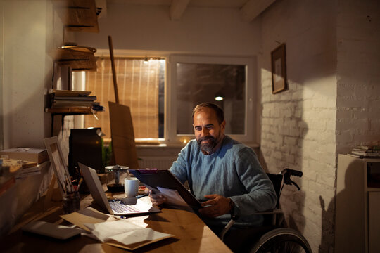 Man in wheelchair reviewing paperwork at home office