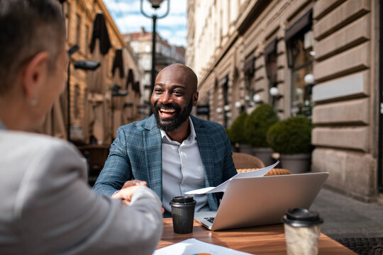 Smiling businessman shakes hands at outdoor cafe meeting