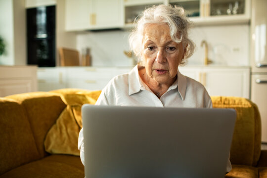 Senior woman concerned while using laptop at home