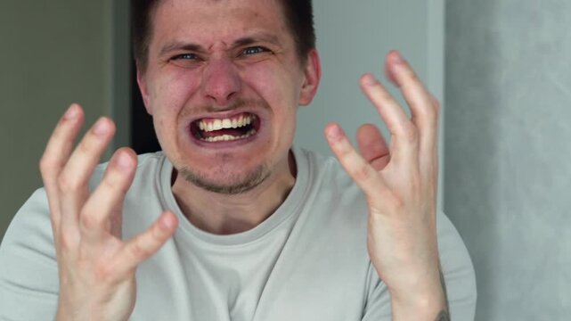 A man standing in a brightly lit room, showing angry emotions.
The man is agitated and shouting.