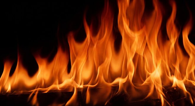 Flames rise dynamically in a vibrant horizontal band, casting a warm orange and yellow glow against a deep black.