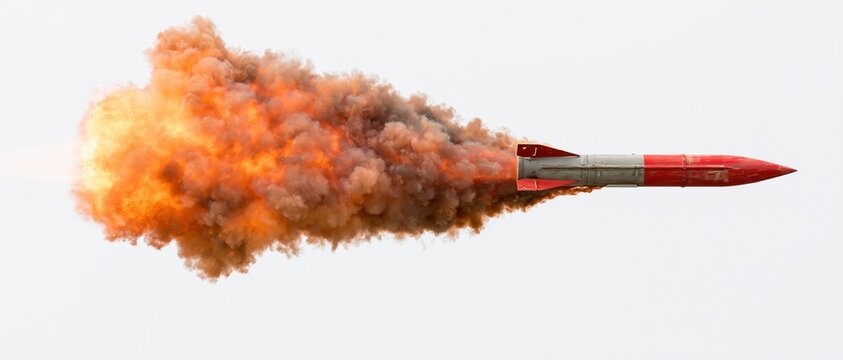 Red military missile in flight with fiery exhaust trail against white background