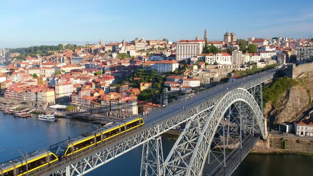 Sunrise morning view of Porto and Ribeira with a tram on Dom Luis I Bridge, river boats on the Douro River, and sunlit bridge deck in Portugal