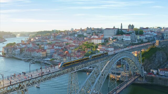 Sunset evening view of Porto and Ribeira with a tram on Dom Luis I Bridge, river boats on the Douro River, and bridge span in Portugal