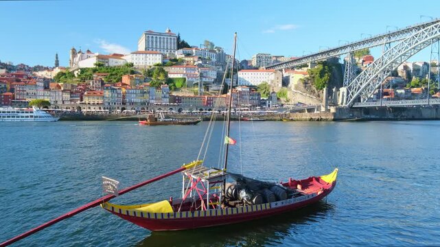 A single rabelo boat on the Douro River by Porto Ribeira, Portugal, with bridge view and Vila Nova de Gaia waterfront