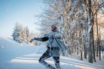 Fototapeta premium Playful man covered in snow enjoying winter fun in snowy woodland.
