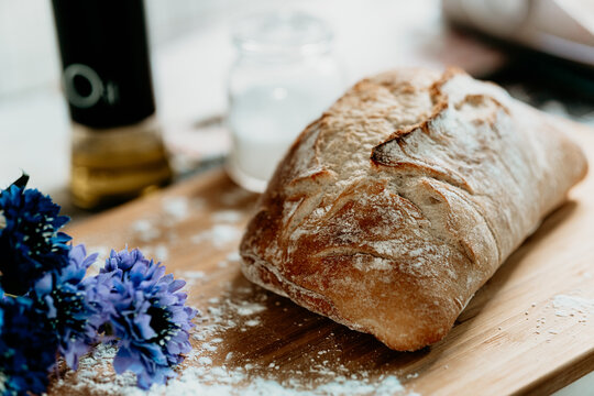 Fresh homemade bread on a wooden board with flour and blue flowers