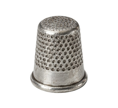 Old metallic sewing thimble with a textured surface is captured in a close-up studio shot on a clean white background