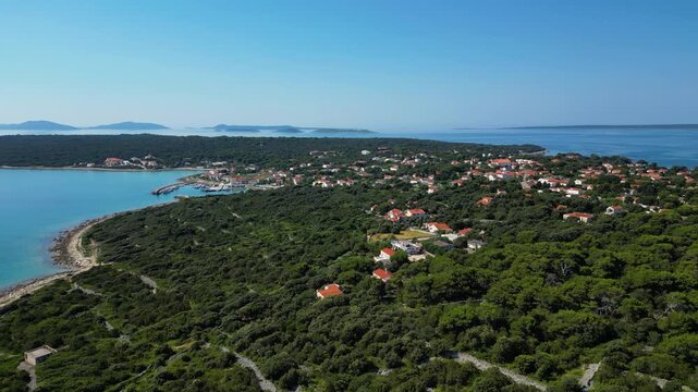 A breathtaking aerial drone panorama of old village on Silba Island, Croatia. The shot showcases the vibrant turquoise harbor, a docked ferry, and the charming coastal village stretching across the