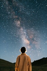 Fototapeta premium Person silhouetted under the milky way night sky in remote landscape for astronomy wallpaper and stargazing background design