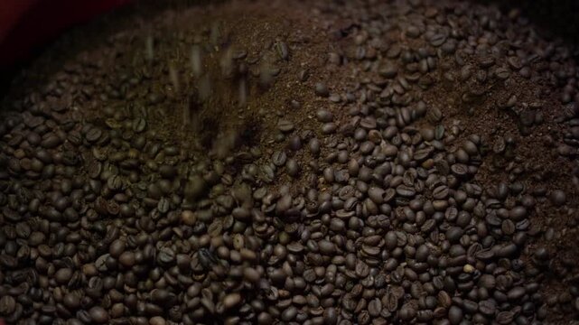 Close up of roasted coffee beans pouring and falling into a pile in slow motion