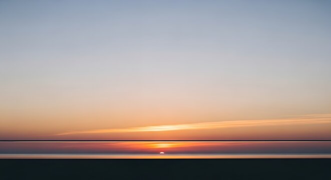 Minimalist seascape at sunrise with simple horizontal layers of soft orange clouds and dark calm ocean water meeting horizon line during tranquil morning twilight over vast empty coastal water.