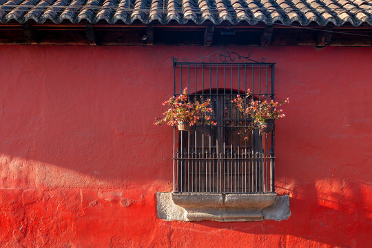 Red colonial style facade with window and flowers, Antigua, Guatemala.
