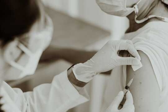 Sepia close up of a vaccination injection into an upper arm