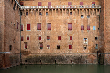 Brick facade of Castello Estense in Ferrara with windows and water moat © Andrea Tabaro