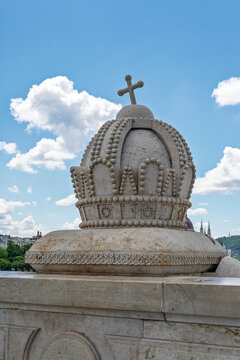 Carved stone sculpture of the Holy Crown of Hungary on a bridge parapet overlooking Castle Hill in Budapest, Hungary