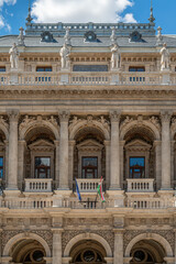 Hungarian and European Union flags on a balcony beneath columned windows at the Budapest Opera House facade © Guillaume Angleraud
