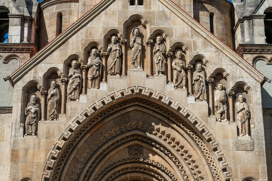 Carved apostle statues in arched niches above the romanesque portal of the Jaki Chapel in Budapest, Hungary