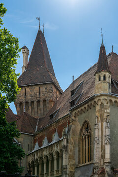 Steep tiled roof and romanesque corbelled tower rising above gothic gables at Vajdahunyad Castle in Budapest