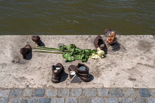 Iron shoes with flowers and candles at the Shoes on the Danube Bank memorial on the river embankment in Budapest, Hungary