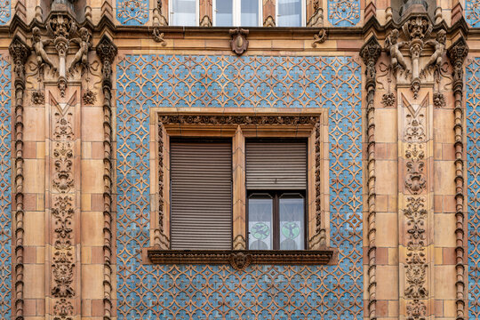 Window with roller shutters framed by blue glazed tiles and carved stone pilasters with masks on Thonet House in Budapest, Hungary