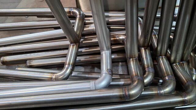 Custom fabricated stainless steel tubes with welded 90-degree elbows in metal factory