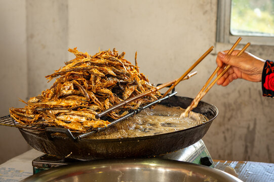 Fresh Small Fish Deep Frying in Large Wok at Traditional Asian Street Food Kitchen