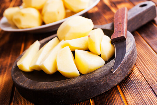 Plate with raw potatoes on wooden background