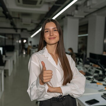Confident Woman with Joyful Smile Giving Thumbs Up in Vibrant Office Setting