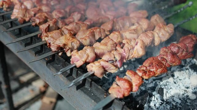 Meat skewers grilling on charcoal barbecue. Shashlik roasting over hot coals with smoke. Traditional outdoor cooking of kebab on brazier grill.