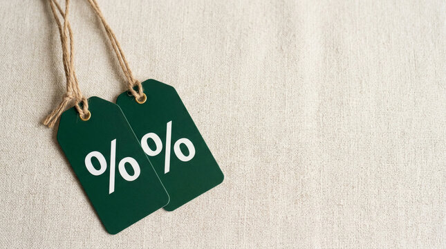 Two green sale tags with percent symbols hang on twine, representing discounts and savings, ideal for retail promotions.