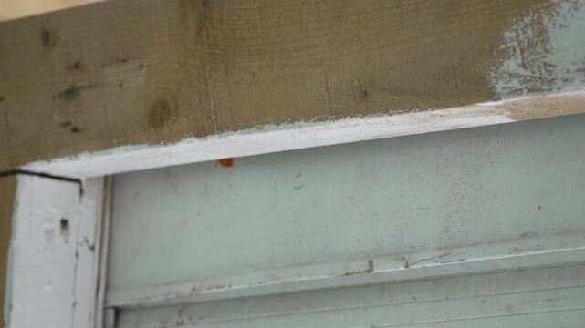 Applying white primer on a wooden frame during a home renovation project. Close-up shot.