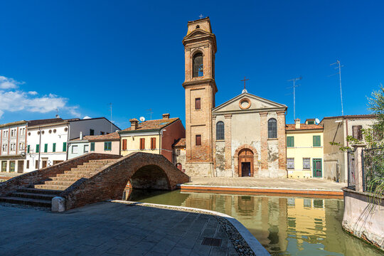 Carmine Church with bell tower and brick bridge over the canal in Comacchio, Italy