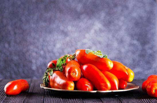 Fresh red tomatoes on plate and on wooden table