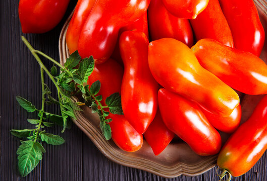 Fresh red tomatoes on plate and on wooden table