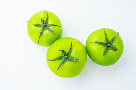 Fresh green tomatoes on a white background