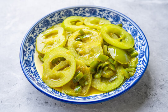 A plate of vegetables on the dining table&mdash;stir-fried green tomatoes.