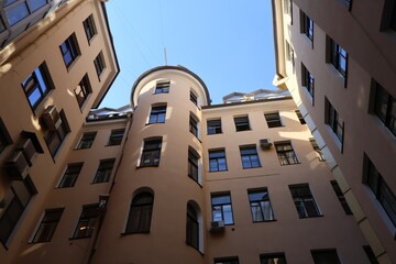 Well courtyard enclosed by beige apartment buildings  a modern glass-paneled structure juts into the frame, contrasting with historic architecture © Semiglass